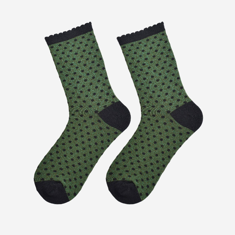 Green socks with black polka dots and cuffs on a white background