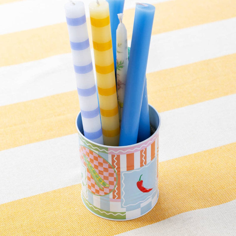 Colorful candles in a patterned holder on a striped tablecloth
