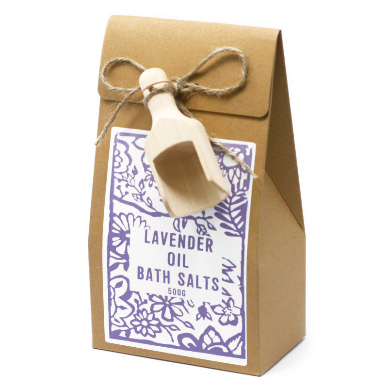 Kraft paper bag with lavender oil bath salts and a wooden scoop on a white background