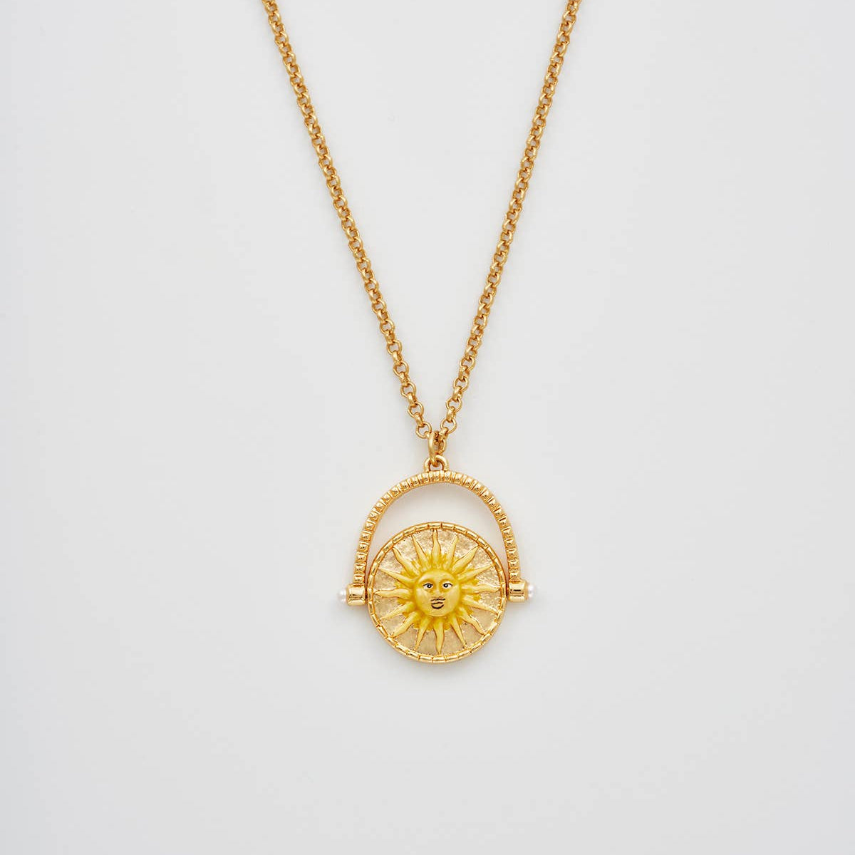 Gold necklace with a sun pendant on a light gray background