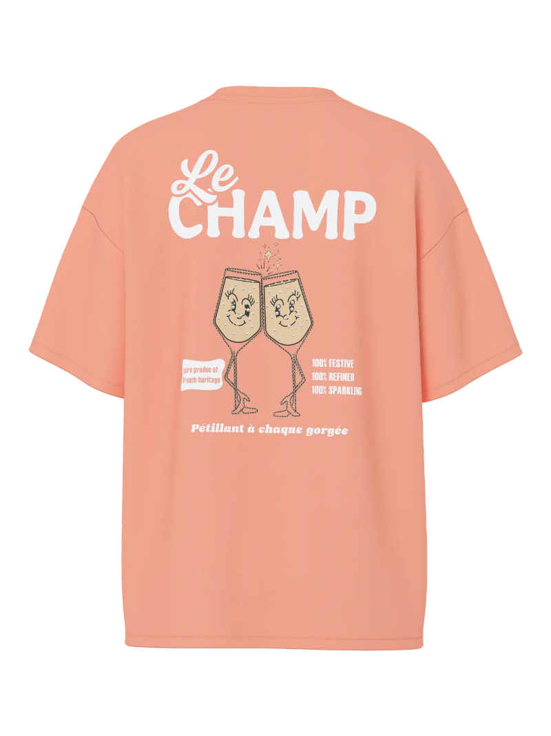 Peach-colored t-shirt with 'Le Champ' text and champagne glass design on a white background