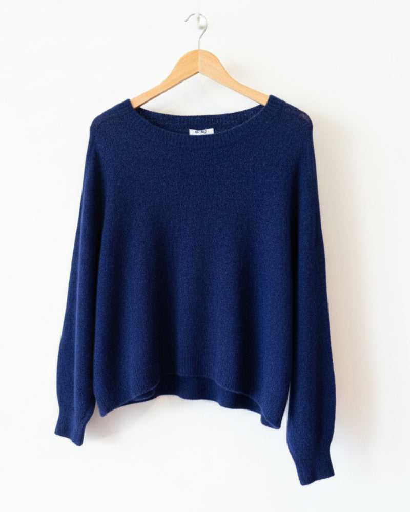 Blue sweater on a hanger against a light wooden panel background