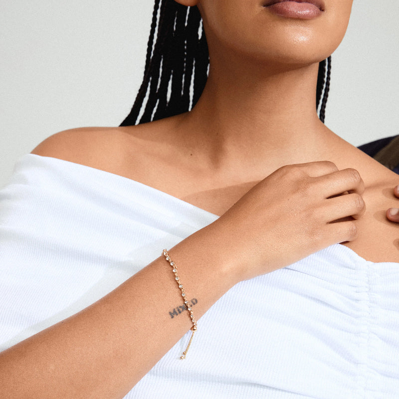 Woman wearing a gold bracelet on a plain background