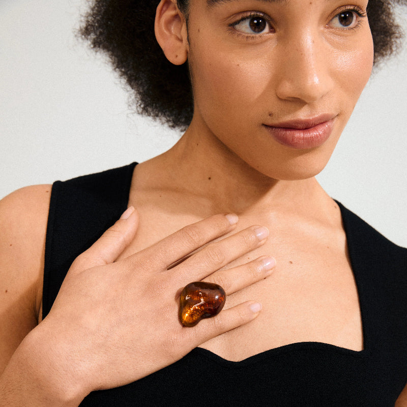 Woman holding a large amber stone against her chest with a neutral background