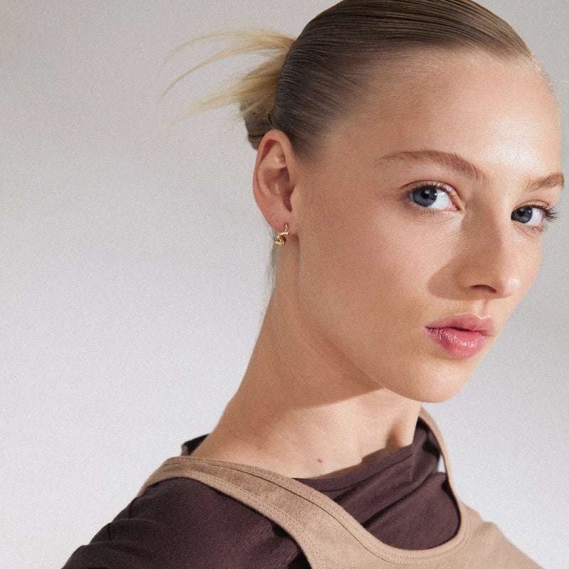 Woman wearing a brown top with a beige collar against a plain background