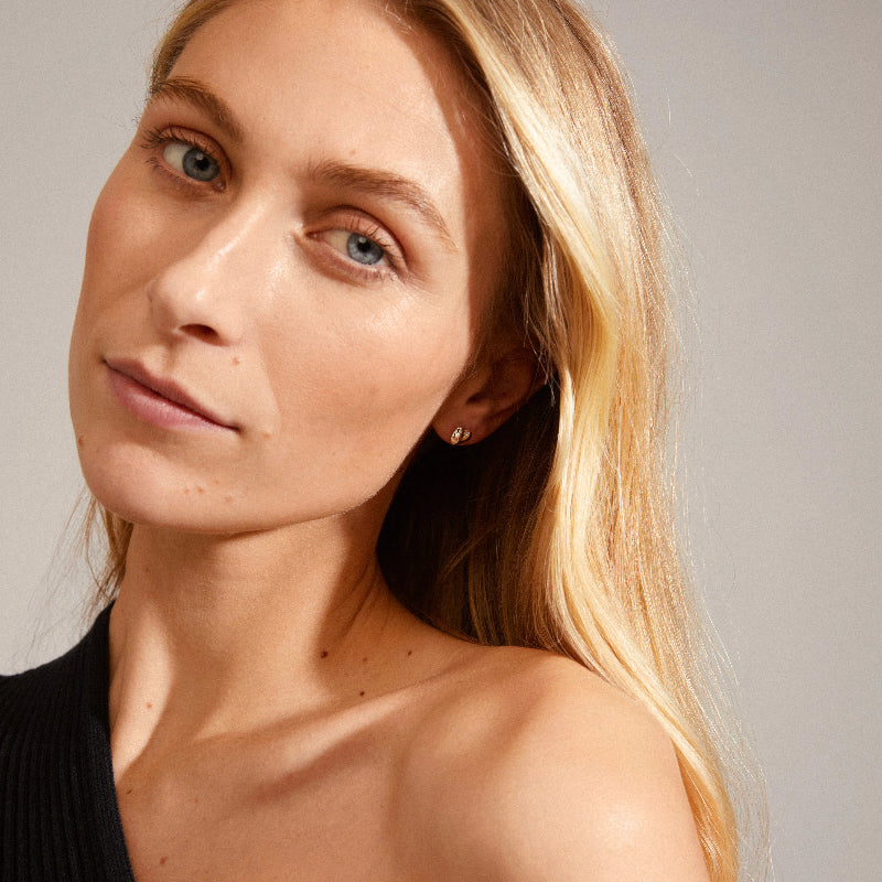 Close-up of a woman with blonde hair and blue eyes against a neutral background