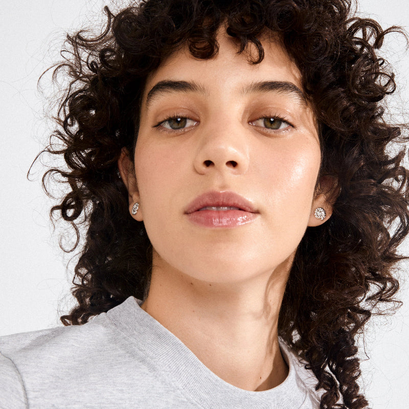 Close-up of a person with curly hair wearing a gray shirt on a white background