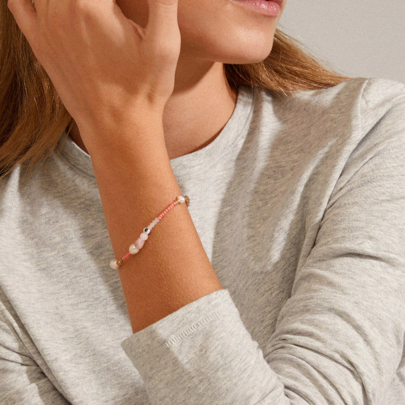 Person wearing a bracelet with small beads on a neutral background