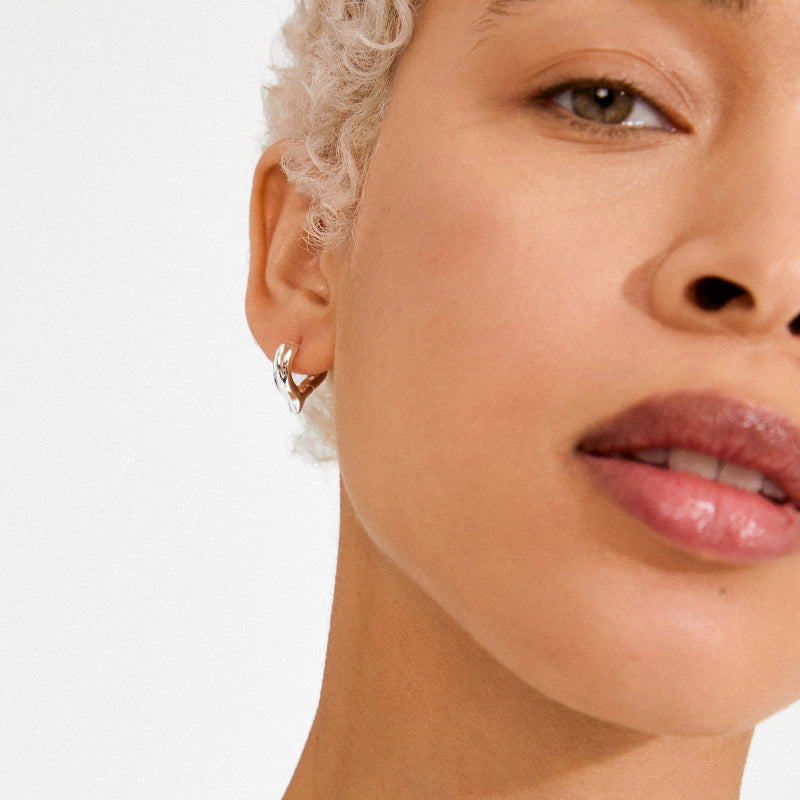 Close-up of a woman's face with a focus on her earrings against a white background