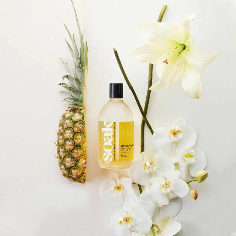 Bottle of 'YEOS' pineapple juice with a pineapple and white flowers on a light background