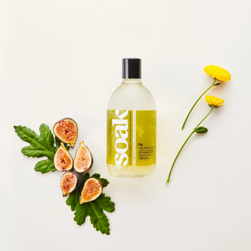 Bottle of Soak laundry detergent with figs, leaves, and flowers on a white background