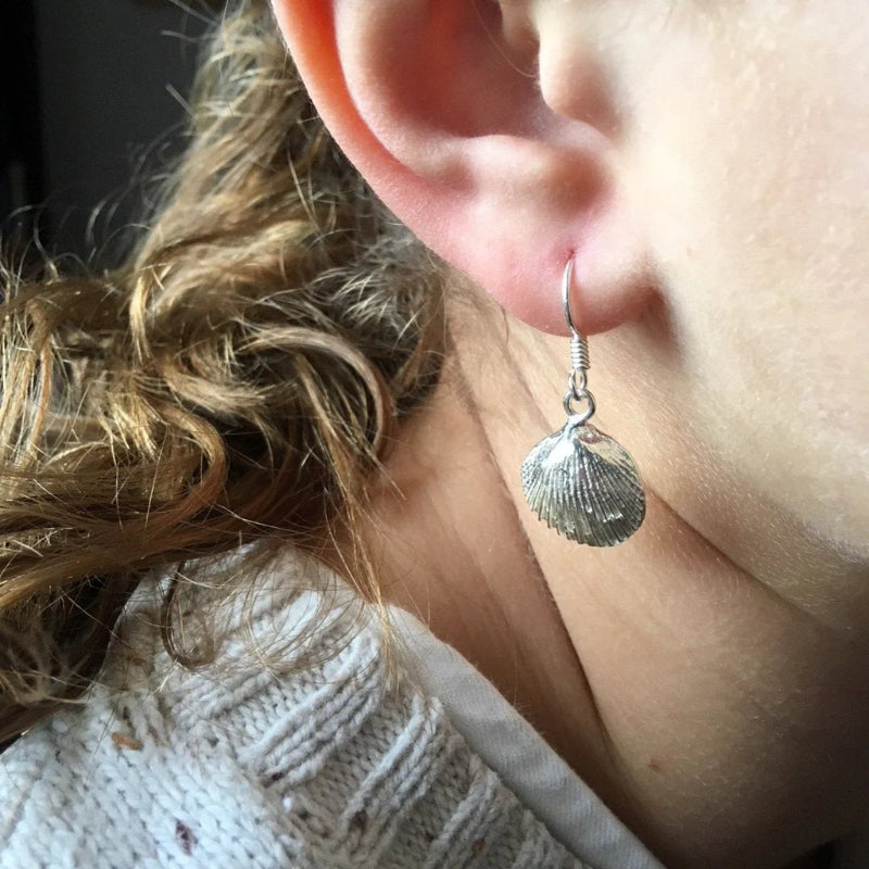 Close-up of an ear wearing a silver shell earring.