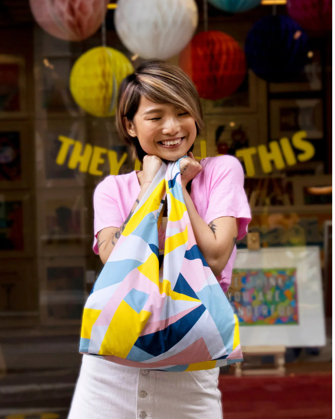 Person holding a colorful striped bag with a festive background