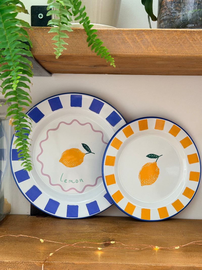 Two decorative plates with lemon designs on a white wall.